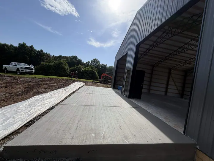 Wide concrete driveway beside a large metal building