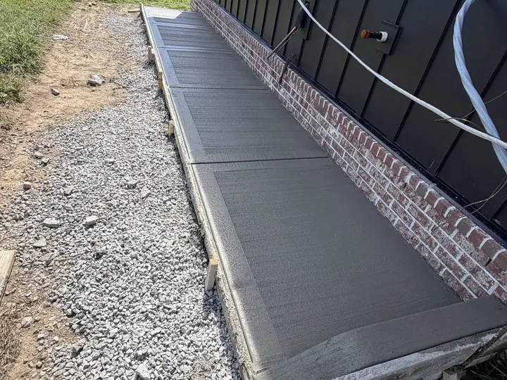 Fresh concrete walkway with defined edges along a building