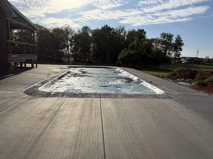 Large finished concrete patio surrounding a pool area