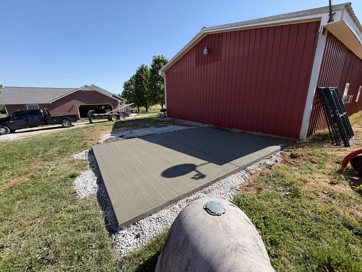 New concrete pad beside a red metal building