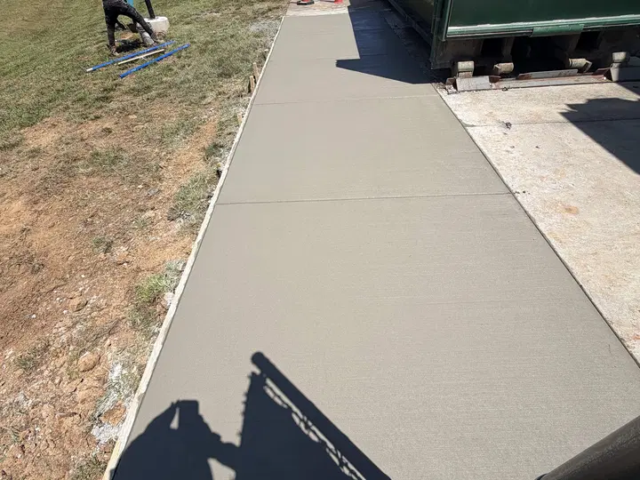 Freshly poured concrete sidewalk with workers nearby