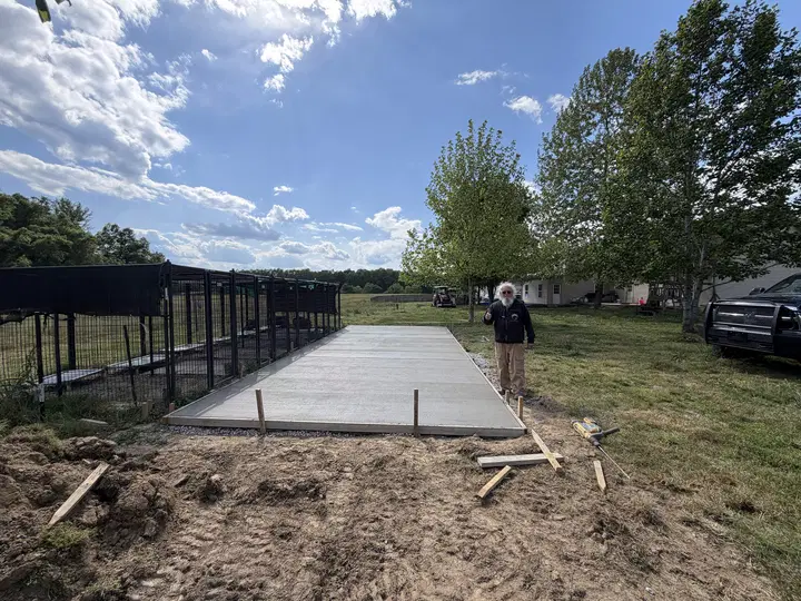 Long newly formed rectangular concrete pad along a fence