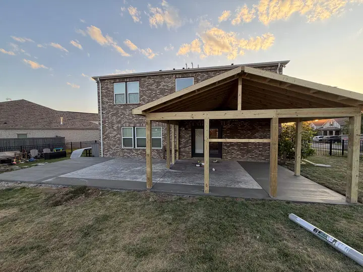 Patio slabs and a covered outdoor space behind a brick home