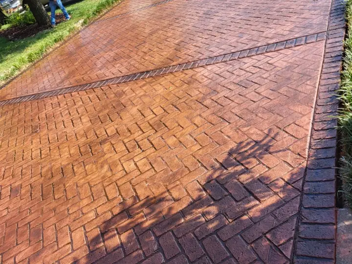 Decorative red stamped concrete driveway with a brick-like pattern