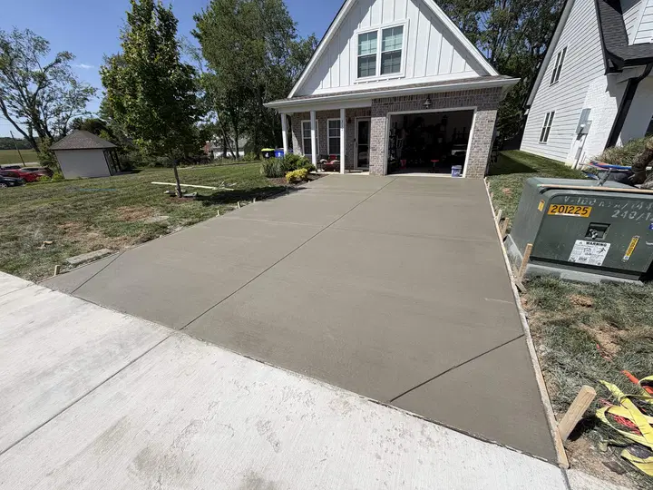 New concrete driveway leading to a white house with attached garage
