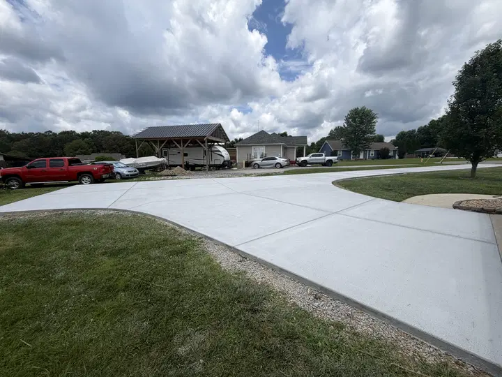 Wide concrete driveway with lawn and surrounding homes